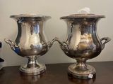 two silver vases sitting on a table next to each other