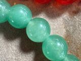 a close up of a necklace with a red and green bead