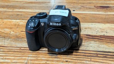 a camera sitting on a wooden table with a flash drive attached to it