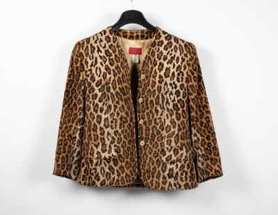 a leopard print jacket hangs on a hanger against a white wall