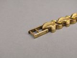 a close up of a gold bracelet with leaves on it