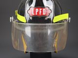 firefighter ' s helmet on a black stand with a clear visor