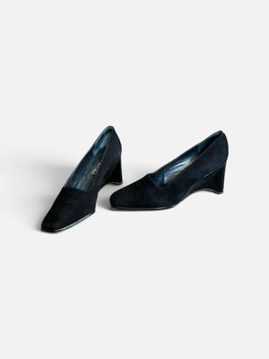 une paire de chaussures en daim noir posées sur une surface blanche