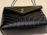 a black leather handbag with a gold y logo on the front