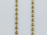 un gros plan d'un collier de perles dorées sur fond blanc