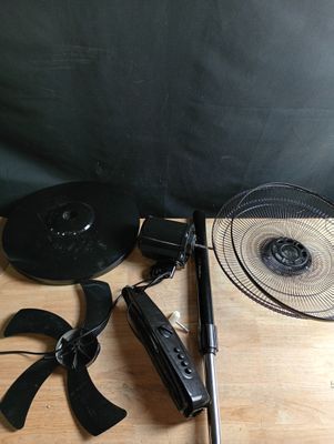 une table sur laquelle se trouvent un ventilateur, une télécommande et d'autres objets