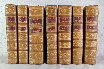 six old books are lined up on a white surface
