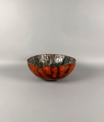 un bol orange et noir posé sur une surface blanche, avec un fond blanc