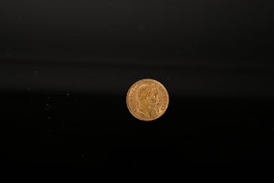 a gold coin floating in the water on a black background
