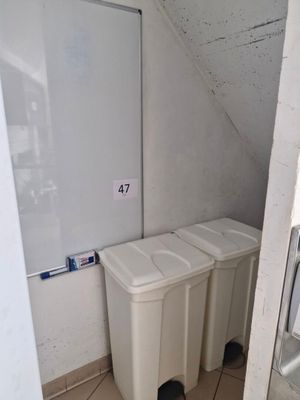 two trash cans in the corner of a bathroom