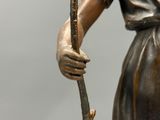 une statue en bronze représentant une femme tenant un bâton