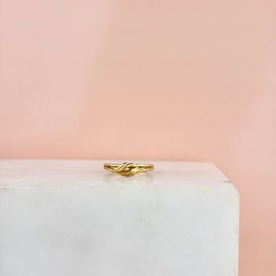 une bague en or posée sur un bloc blanc