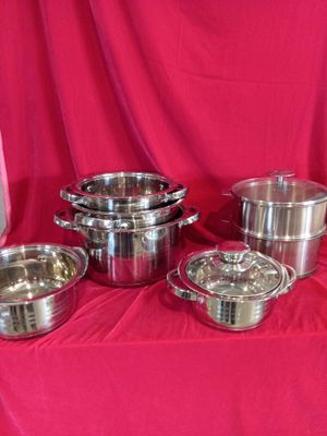 several stainless steel pots and pans on a red cloth