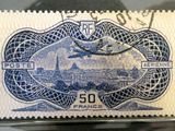 the stamp is blue and white with a picture of a plane flying over a city