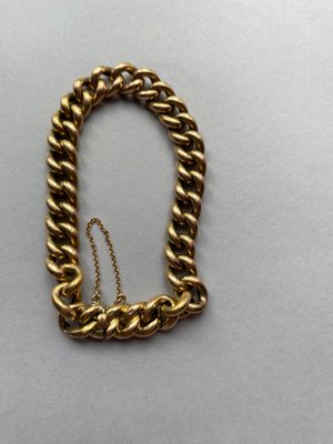 gros plan d'un bracelet en chaîne en or sur une surface blanche