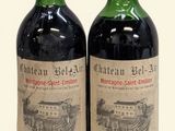 two bottles of red wine sitting next to each other on a white surface