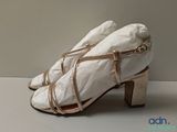a pair of white shoes with gold straps on them