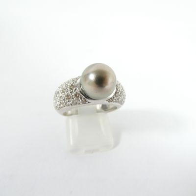 gros plan d'une bague en perles et diamants sur une surface blanche