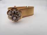 a close up of a gold bracelet with a flower on it