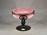 a pink glass bowl on a black stand on a gray background