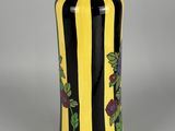 yellow and black striped vase with flowers and leaves on it
