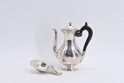 une cafetière et une cuillère en argent posées sur une surface blanche