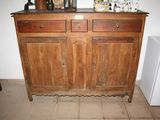 a wooden cabinet with two drawers and a small refrigerator in the corner