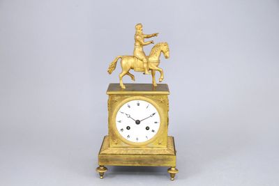 une horloge en or surmontée d'une statue représentant un homme à cheval