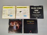 four rolling stones album covers and booklets on a table