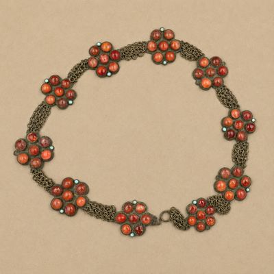 un gros plan d'un collier composé de perles rouges sur fond marron