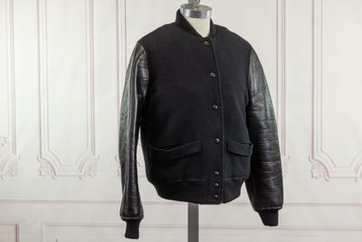 a black jacket on a mannequin stand in front of a white wall