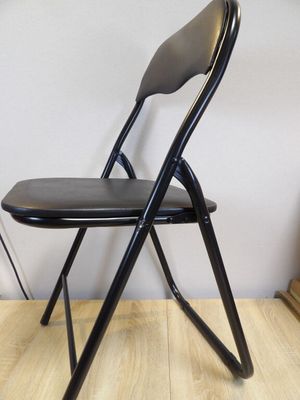 une chaise pliante noire avec une assise noire posée sur un parquet