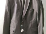 grey suit jacket hanging on a hanger on a white wall