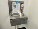 a stainless steel sink in the corner of a bathroom