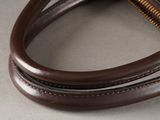 brown leather handbag with a zipper on a gray surface