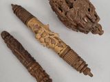 three carved wooden objects on a white surface including a pen and a ballpoint pen