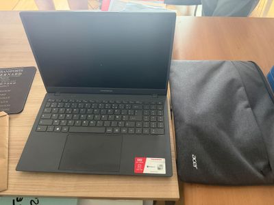un ordinateur portable posé sur une table, à côté d'un sac