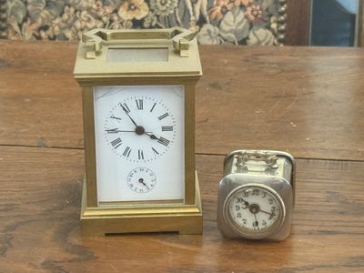a small clock sitting next to a small clock on a table