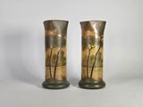 two tall vases with trees painted on them sitting on a table