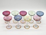 several different colored wine glasses are lined up on a white surface