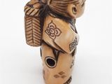 wooden figurine of a woman with a backpack on her back