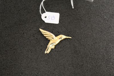 a gold hummingbird brooch with a tag on it