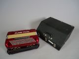 an image of a red accordion and a black case on a white surface