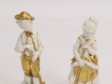 pair of porcelain figurines of a boy and a girl playing musical instruments