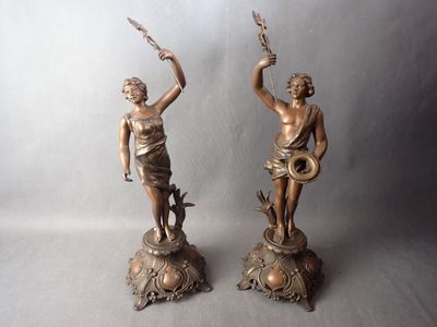 pair of antique bronze figurines of a woman holding a sword and a bird