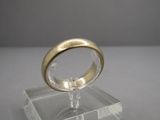une bague en or posée sur un socle transparent