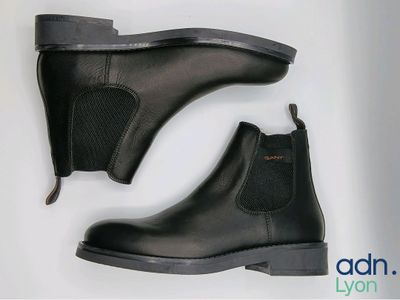 une paire de bottines Chelsea en cuir noir sur fond blanc