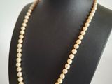 a white pearl necklace on a black mannequin with a gold clasp