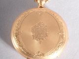 a gold pocket watch with a chain on a white surface