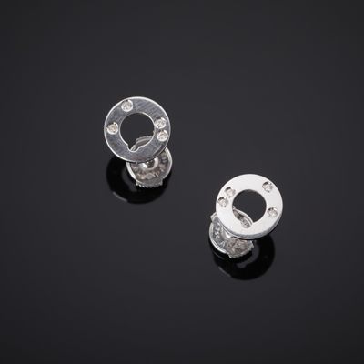 une paire de boucles d'oreilles en argent et diamants posées sur une surface noire